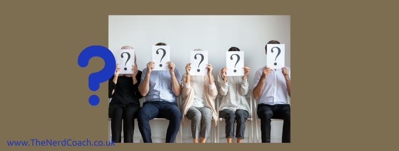Picture of a line of people sat in chairs holding up question marks